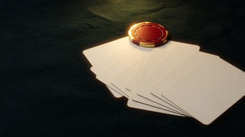 Bone-white cards fanned on dark felt with a gold-rimmed chip