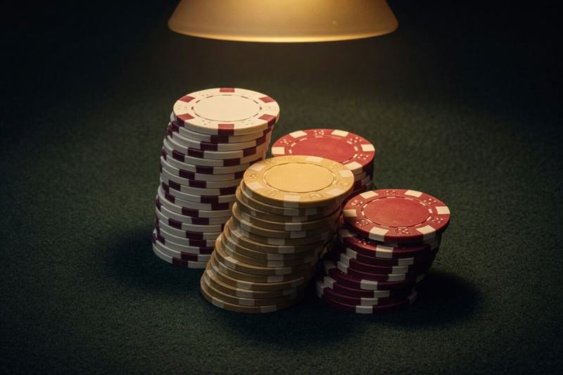 Stacks of gold and burgundy poker chips under a table lamp