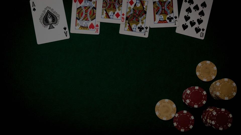 Overhead green felt with face-up playing cards along the top and chip stacks at the lower right