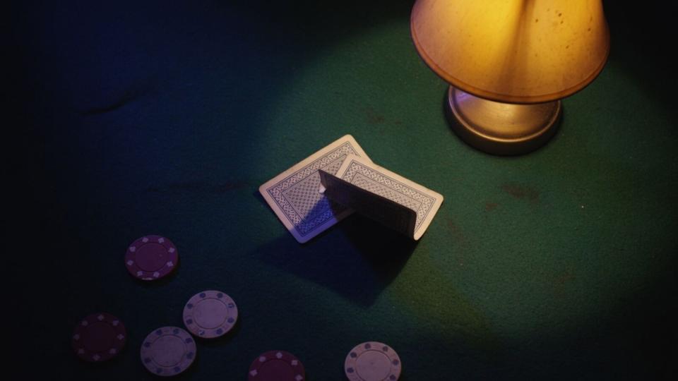 Mucked cards under a dying lamp on green felt